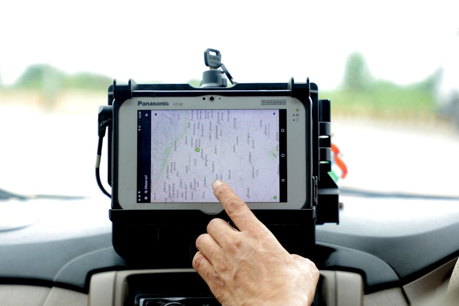 Close-up of hand interacting with GPS navigation on a car-mounted tablet screen, showcasing modern technology.